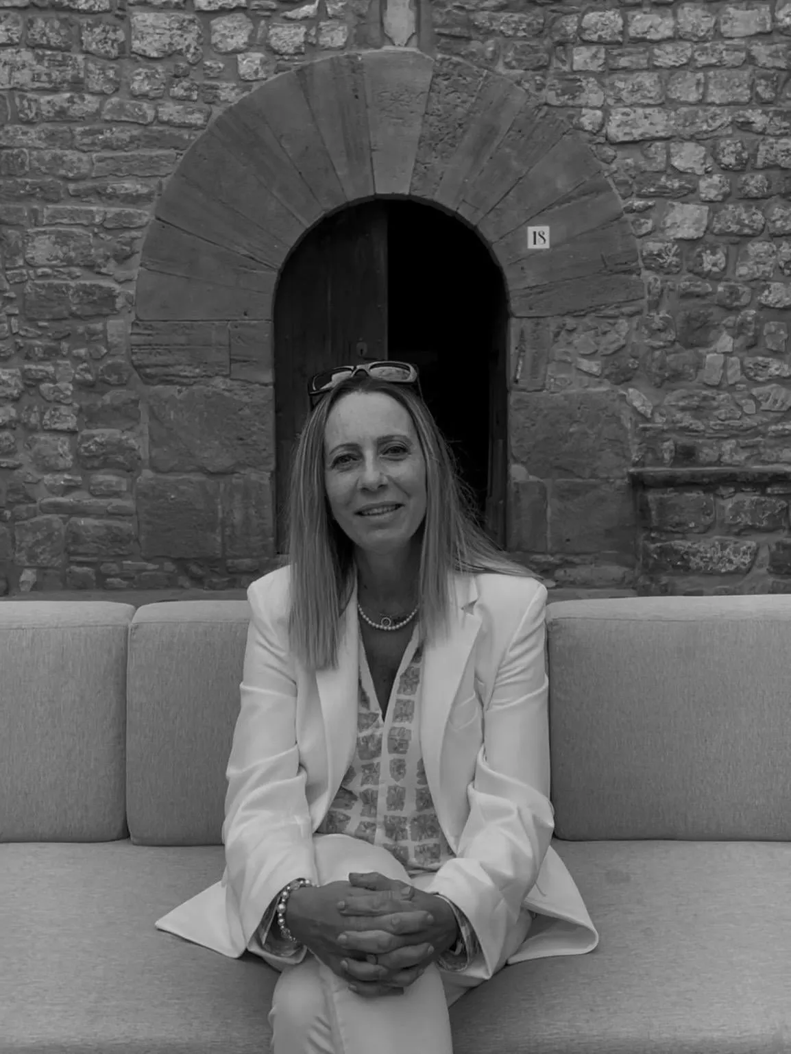 Black and white portrait of Pilar, wedding planner at Pilove Wedding, sitting in front of a stone doorway